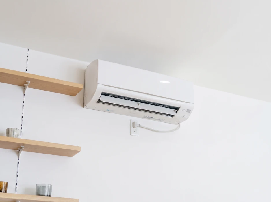Climatiseur mural de type split-system monté en hauteur sur un mur blanc intérieur, vents orientables ouverts
