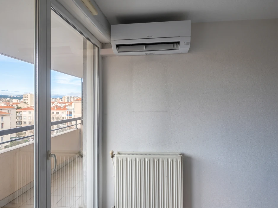 Appartement en hauteur, pièce vide avec vue urbaine panoramique via baie vitrée coulissante donnant sur un balcon