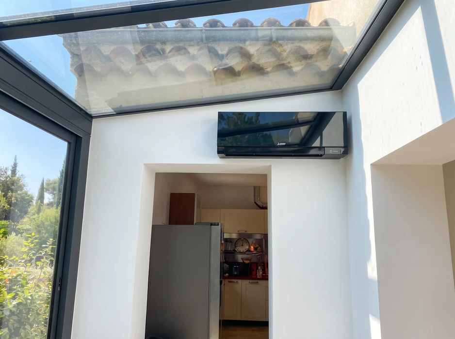 Véranda lumineuse avec toit vitré, murs blancs et menuiseries anthracite