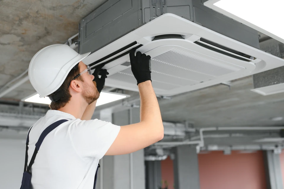 Extérieur résidentiel avec unité de climatisation installée contre mur en briques beiges