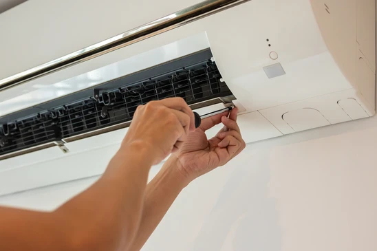 Technicien climaticien professionnel en tenue de travail, équipé d'un presse-papiers et d'outils de diagnostic, effectuant une visite d'étude dans un salon résidentiel. Il est en conversation bienveillante avec le propriétaire des lieux, examinant la pièce et ses caractéristiques (fenêtres, murs, exposition) pour évaluer les besoins en climatisation. L'atmosphère est professionnelle, de confiance, montrant une écoute active et une expertise technique. L'environnement est un intérieur résidentiel moderne et lumineux, typique du bassin marseillais méditerranéen.
