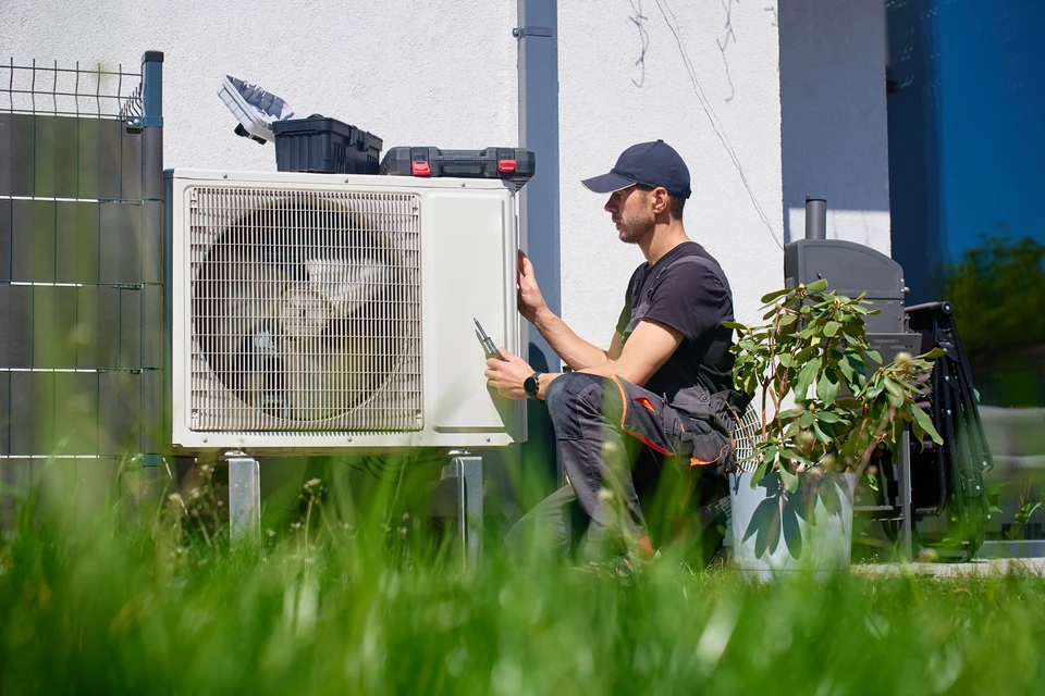 Scène extérieure résidentielle avec unité de climatisation centrale installée sur dalle béton dans jardin