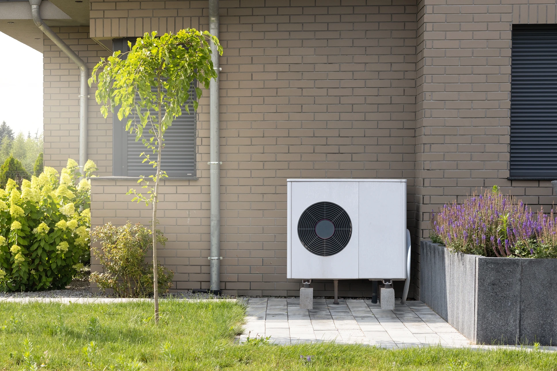 Unité extérieure de climatisation installée sur terrasse béton contre mur blanc